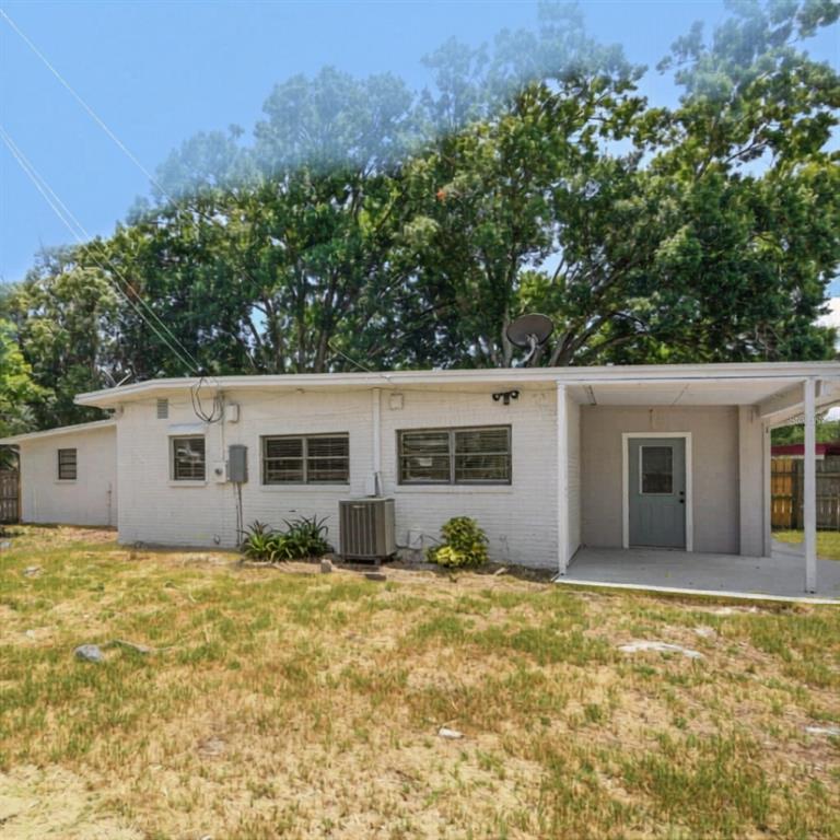A white brick house exterior with a covered porch, an air conditioning unit, and trees — 1202 PRINCETON RD, COCOA, FL