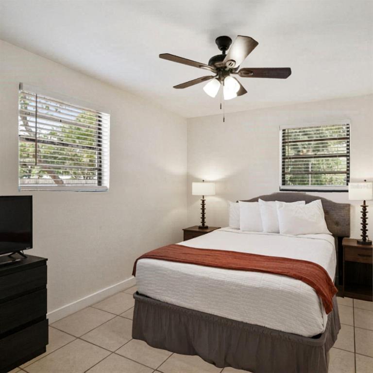 A bedroom features a bed with white linens, a brown runner, and two bedside lamps — 1202 PRINCETON RD, COCOA, FL