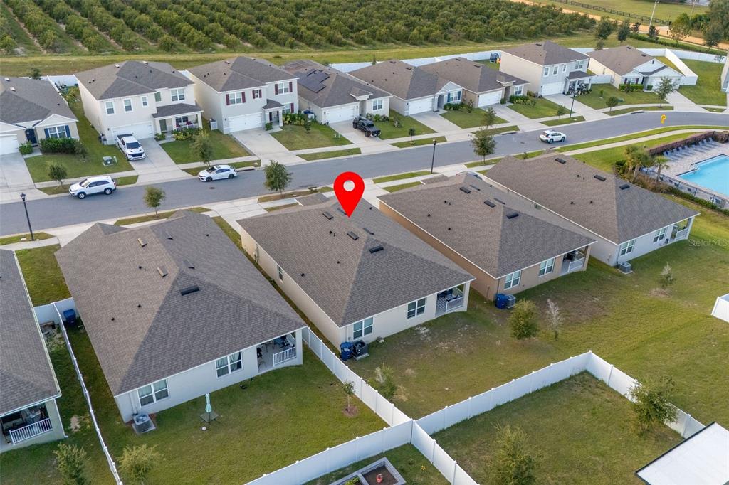 An aerial view shows a suburban neighborhood with houses, fenced backyards, and a community pool — 9537 BLACK WALNUT DRIVE, CLERMONT, FL