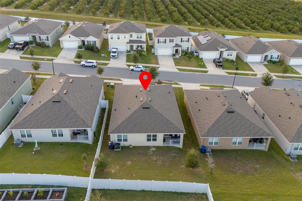 An aerial view shows the rear exterior of a suburban house with a red pin — 9537 BLACK WALNUT DRIVE, CLERMONT, FL