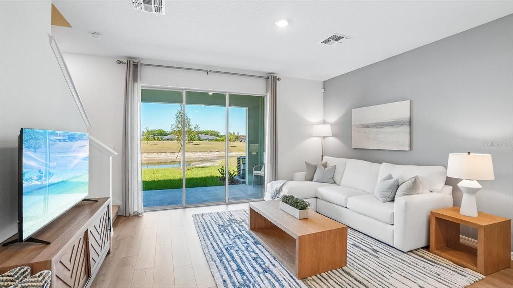 A living room features a white sectional sofa, wood coffee table, and sliding glass doors — 12609 CITRUS PARK LANE, TAMPA, FL