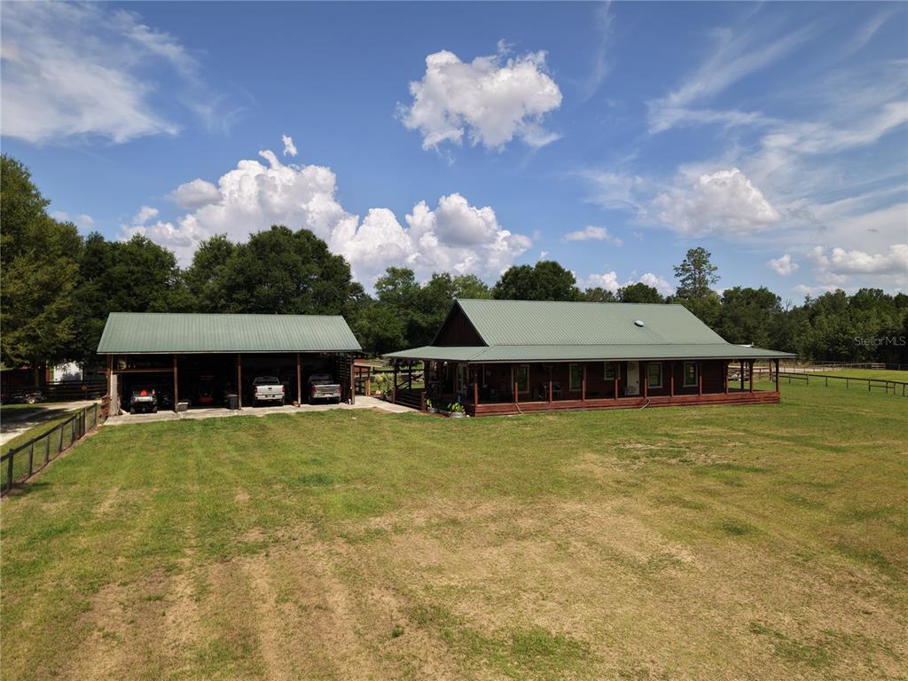 A long, wooden horse barn with a green metal roof and solar panels — 7191 NE 150TH AVENUE, WILLISTON, FL