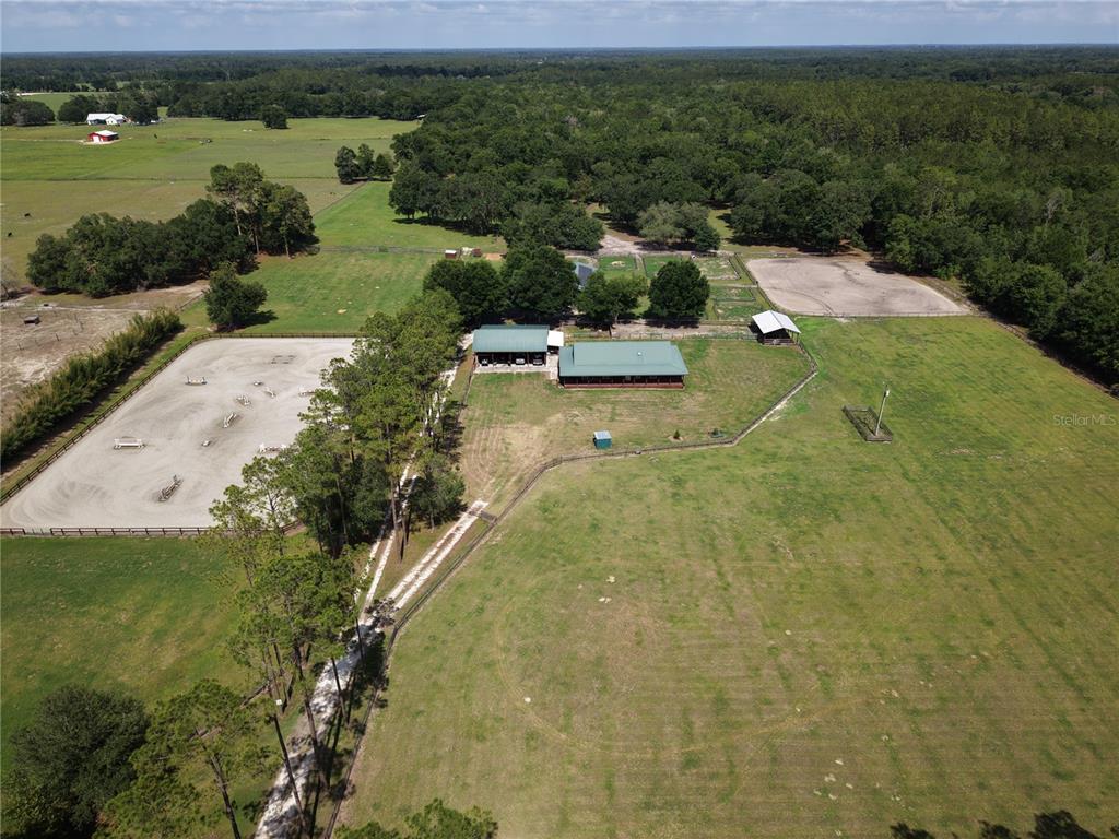 A gravel driveway leads toward a house and barn on a grassy, tree-lined property — 7191 NE 150TH AVENUE, WILLISTON, FL
