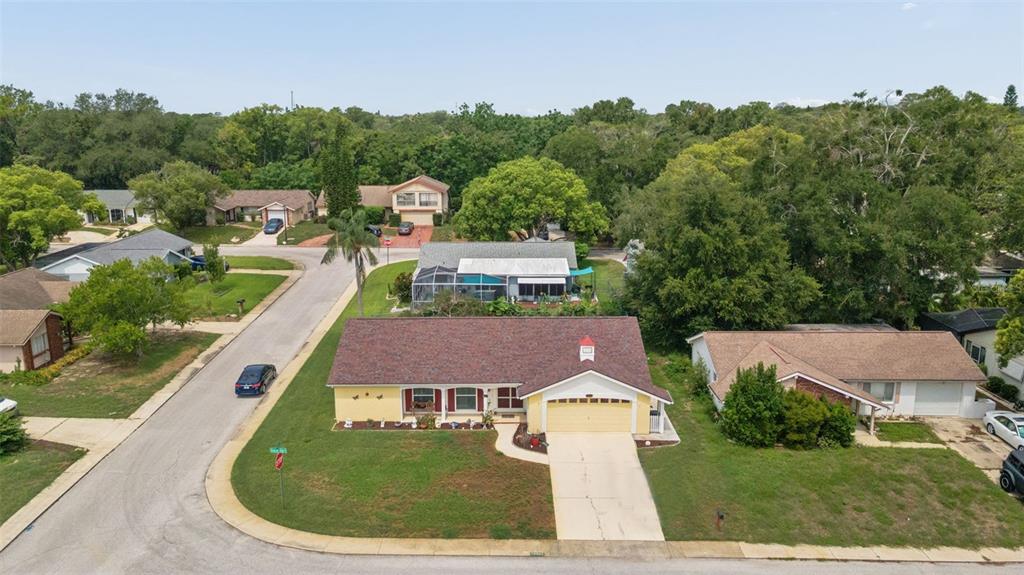 An aerial view of a yellow single-story house with a brown roof and a driveway — 12301 HOUNDS BAY ROW, HUDSON, FL