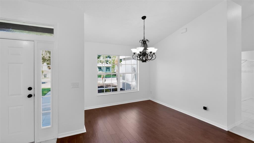A dining room with white walls, dark wood flooring, a chandelier, and a front door — 3325 INDIAN TRAIL, EUSTIS, FL