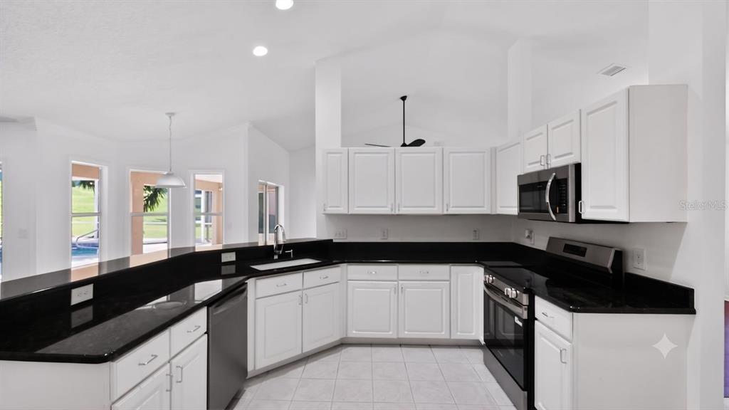 A kitchen with white cabinets, black countertops, and stainless steel appliances — 3325 INDIAN TRAIL, EUSTIS, FL