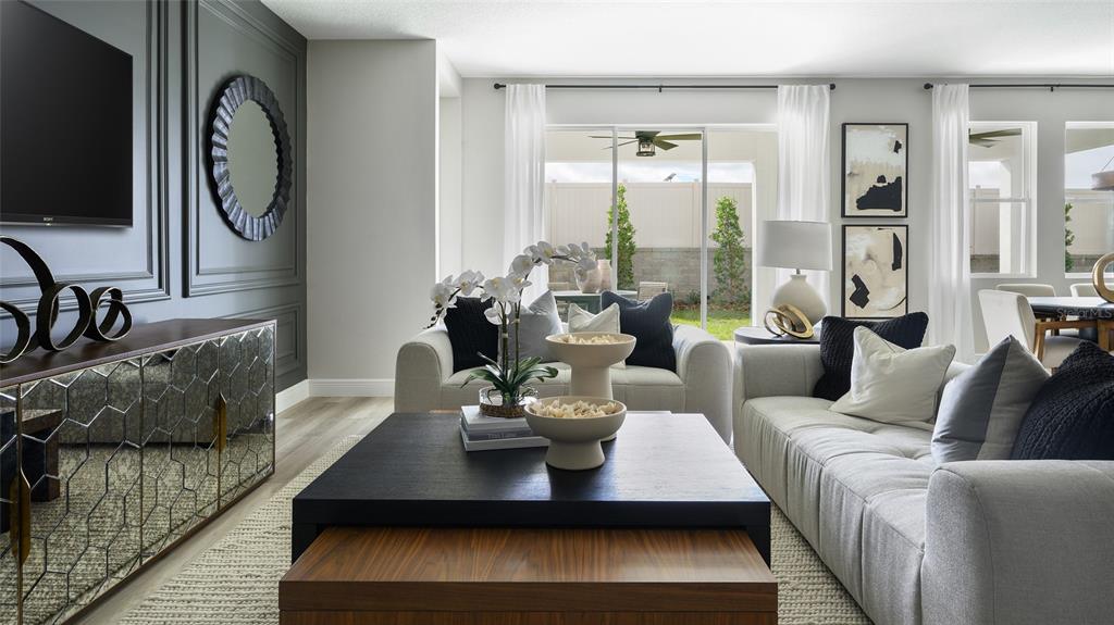 A living room features a dark accent wall, mirrored console, and two light-colored sofas — 33607 TWILIGHT SEA PLACE, DADE CITY, FL