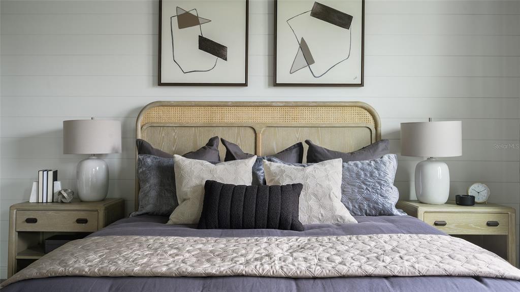 A bedroom features a cane headboard, shiplap wall, two nightstands, and abstract framed art — 33607 TWILIGHT SEA PLACE, DADE CITY, FL
