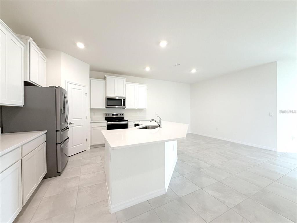A modern kitchen features white cabinets, stainless steel appliances, and a central island with countertops — 4730 NW 39TH STREET ROAD, OCALA, FL