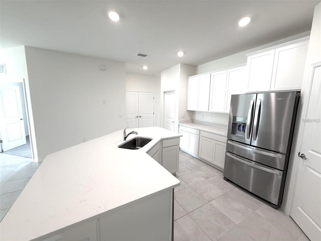 A modern kitchen features white cabinets, stainless steel appliances, and a large central island — 4730 NW 39TH STREET ROAD, OCALA, FL