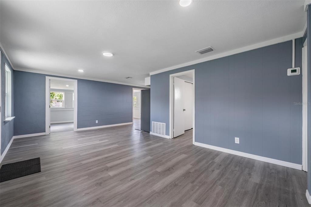 An interior room with gray walls, wood-look flooring, recessed lighting, and multiple doorways — 636 STREMMA ROAD, LARGO, FL
