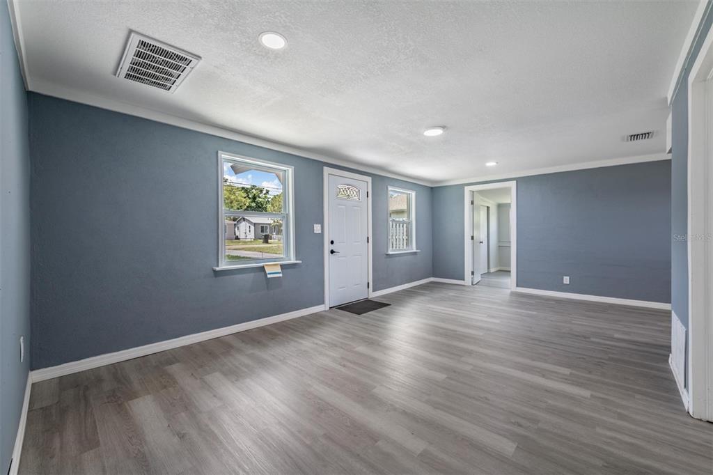 A living room with blue walls, light wood-look flooring, a white front door, and recessed lighting — 636 STREMMA ROAD, LARGO, FL