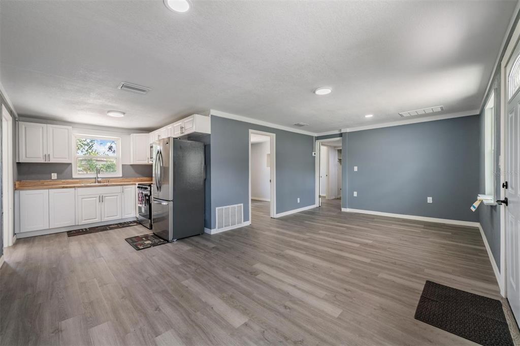 An open-concept kitchen and living area features gray walls, white cabinets, and wood-look flooring — 636 STREMMA ROAD, LARGO, FL