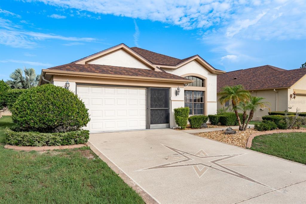 A single-story house with a white garage, a decorative star on the driveway, and landscaping — 13825 LEROUX DRIVE, HUDSON, FL