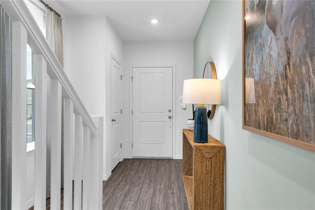 A bright entryway features a white front door, a wooden console table, and a staircase — 3032 JESSAMINE DRIVE, TAVARES, FL