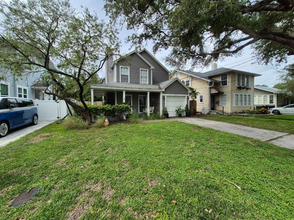 A two-story gray house with a front porch and attached garage sits on a lawn — 2910 W SITIOS STREET, TAMPA, FL