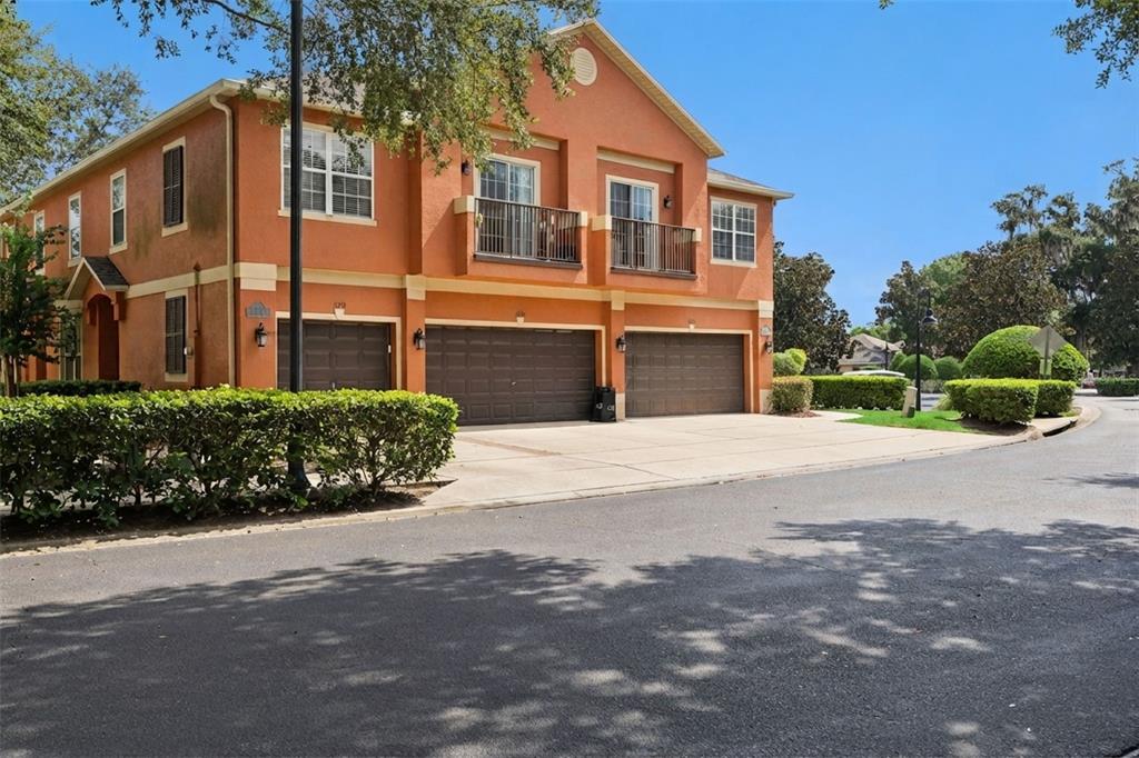 A two-story orange stucco building with three garage doors and two upper-level balconies — 1610 PINE OAK TRAIL, SANFORD, FL