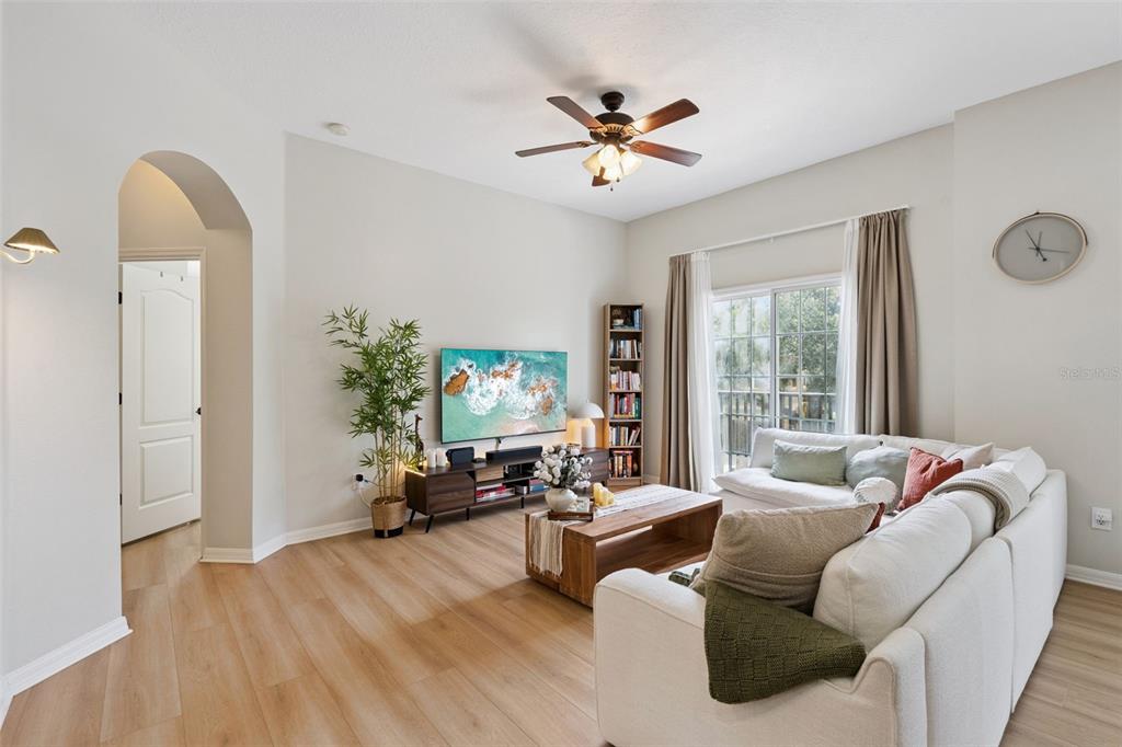A living room features light wood flooring, a white sectional sofa, and a wall-mounted television — 1610 PINE OAK TRAIL, SANFORD, FL