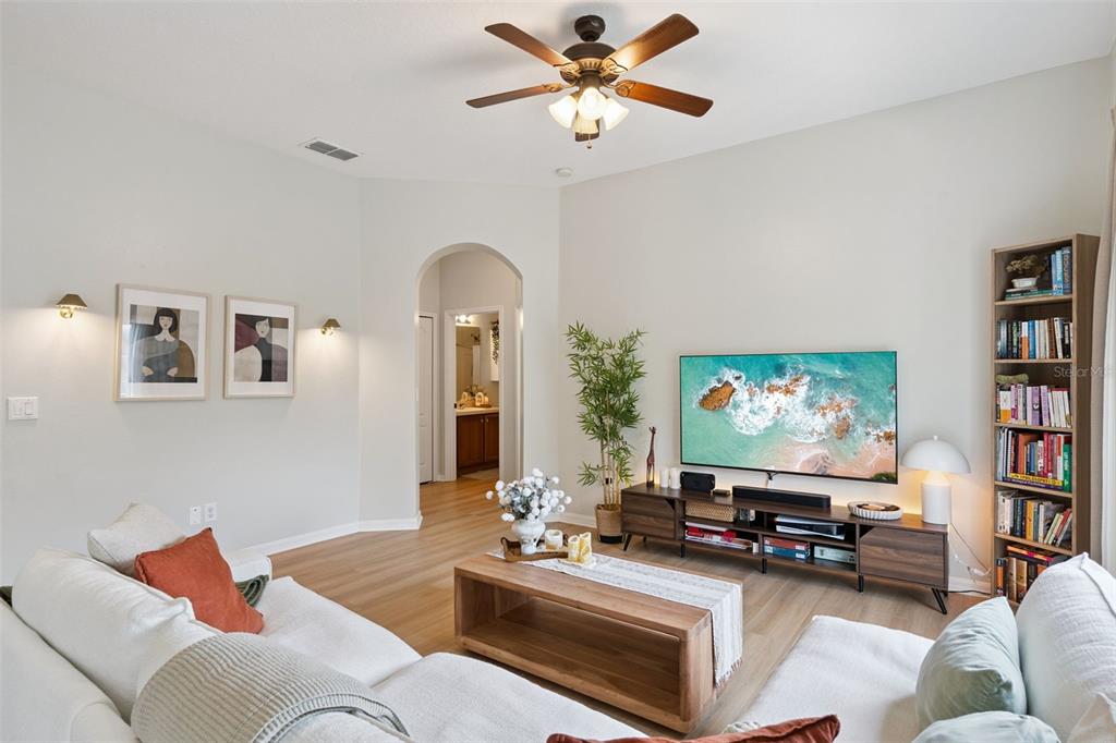 A living room features a ceiling fan, a television on a media console, and bookshelves — 1610 PINE OAK TRAIL, SANFORD, FL