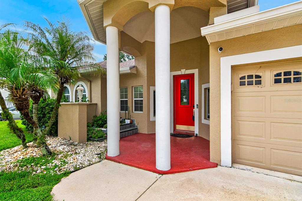 The exterior of a house features a red front door, white columns, and a garage — 2007 RIVER CROSSING DRIVE, VALRICO, FL