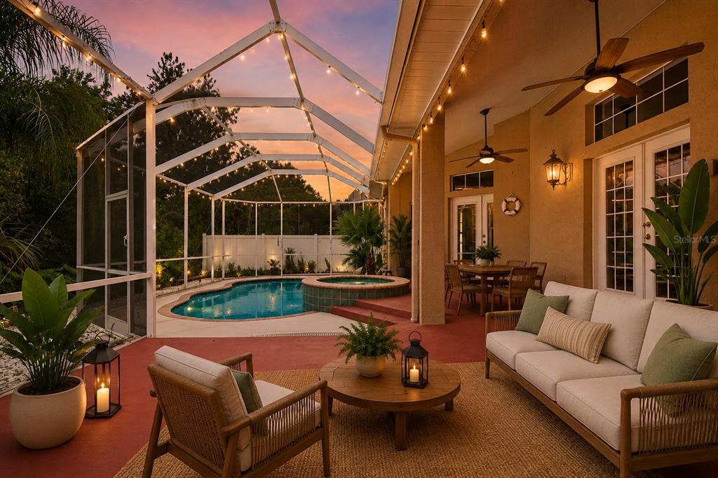 A covered patio features a pool, hot tub, outdoor seating, and string lights at sunset — 2007 RIVER CROSSING DRIVE, VALRICO, FL