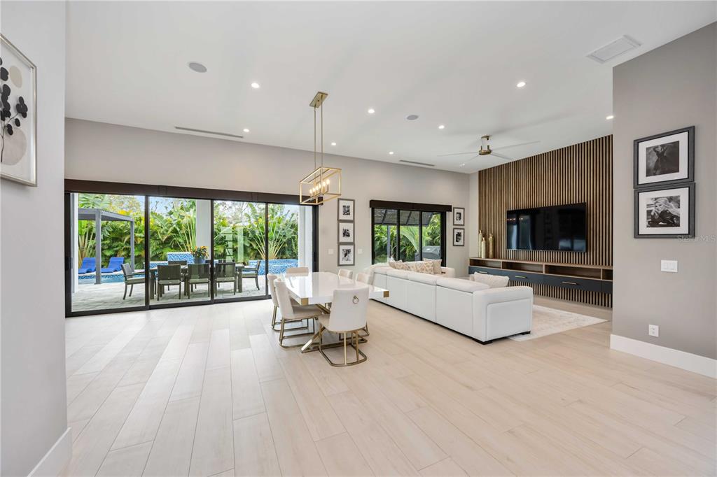 A modern open-concept living and dining area features light wood floors and a slat-wood wall — 2314 PROSPECT STREET, SARASOTA, FL