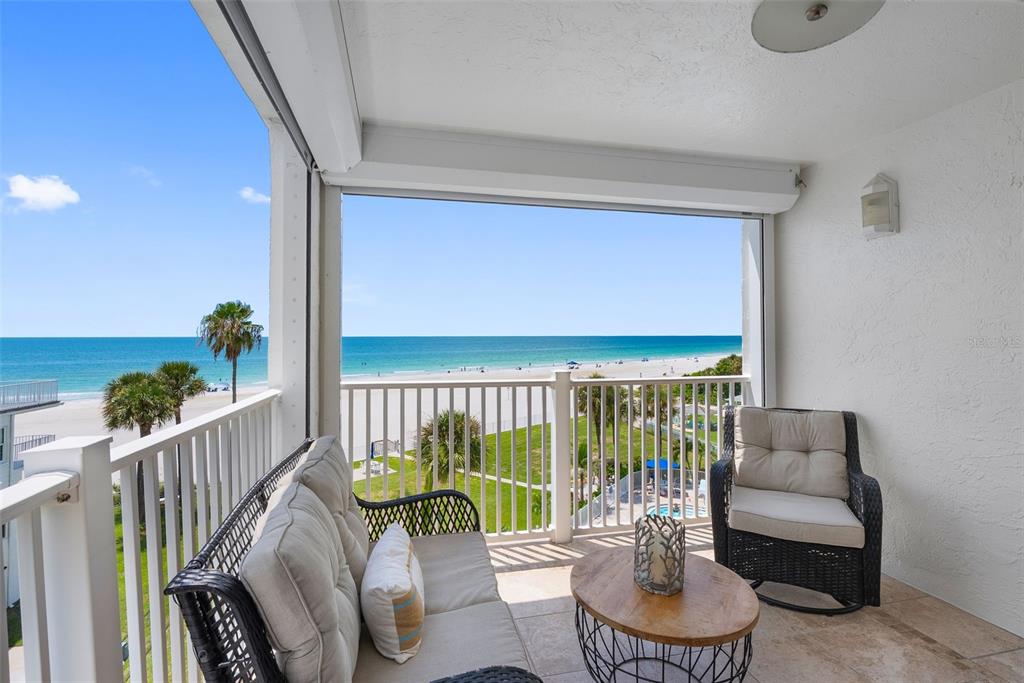 A balcony with outdoor furniture overlooks a sandy beach and the ocean — 17980 GULF BOULEVARD UNIT 401, REDINGTON SHORES, FL