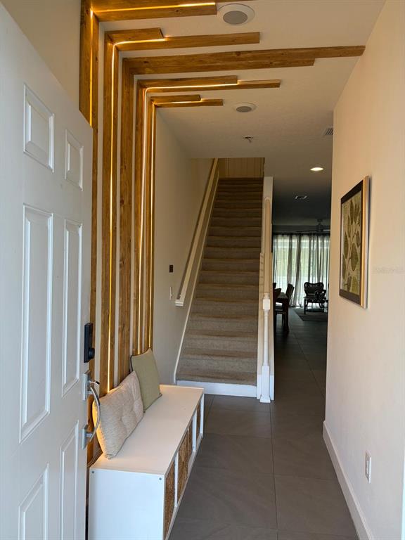 An entryway features a white bench, a carpeted staircase, and wood slats with integrated lighting — 1537 TRANQUIL AVENUE, CLERMONT, FL