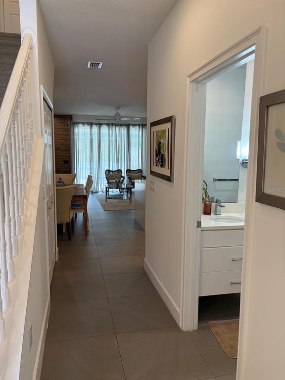 A hallway with tile floors leads to a dining area and a bathroom with a vanity — 1537 TRANQUIL AVENUE, CLERMONT, FL