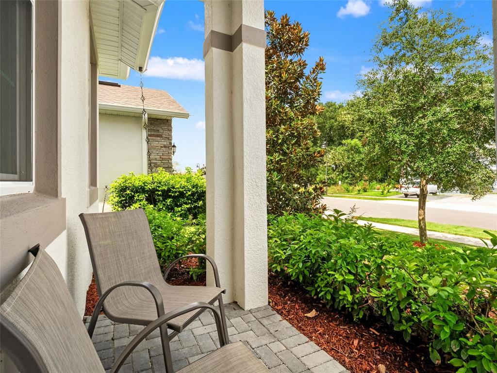 A covered patio features two chairs on a paver floor with views of landscaping and trees — 2325 SIRENA LANE, MOUNT DORA, FL
