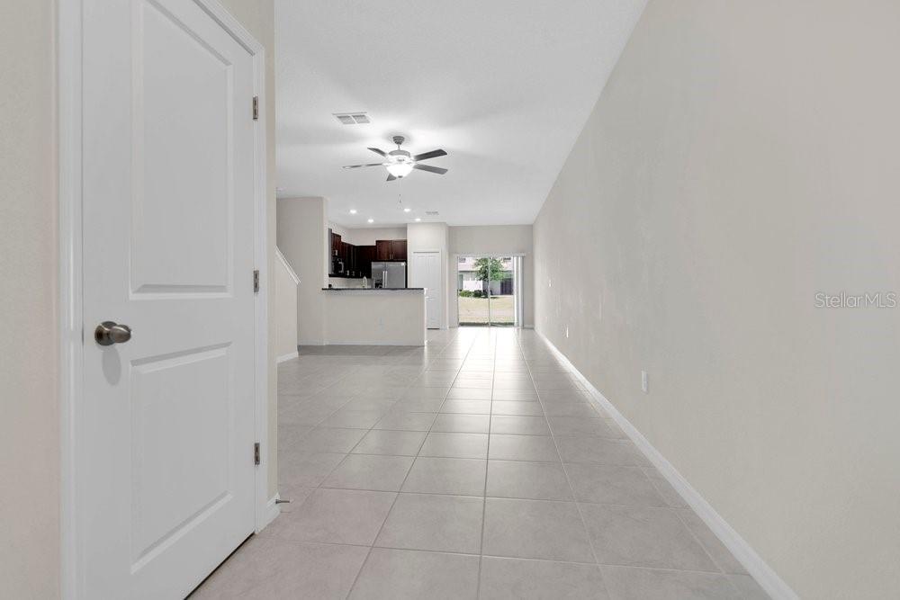 An open-concept living area features light tile flooring, neutral walls, and a kitchen in back — 9640 MULBERRY MARSH LANE, SUN CITY CENTER, FL