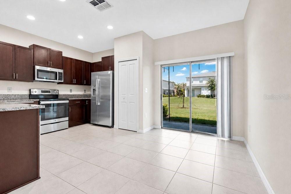 A kitchen with dark wood cabinets, stainless steel appliances, and a sliding glass door — 9640 MULBERRY MARSH LANE, SUN CITY CENTER, FL