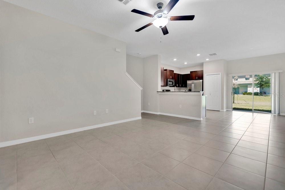 An open-concept living area with light tile flooring, a ceiling fan, and an adjacent kitchen — 9640 MULBERRY MARSH LANE, SUN CITY CENTER, FL