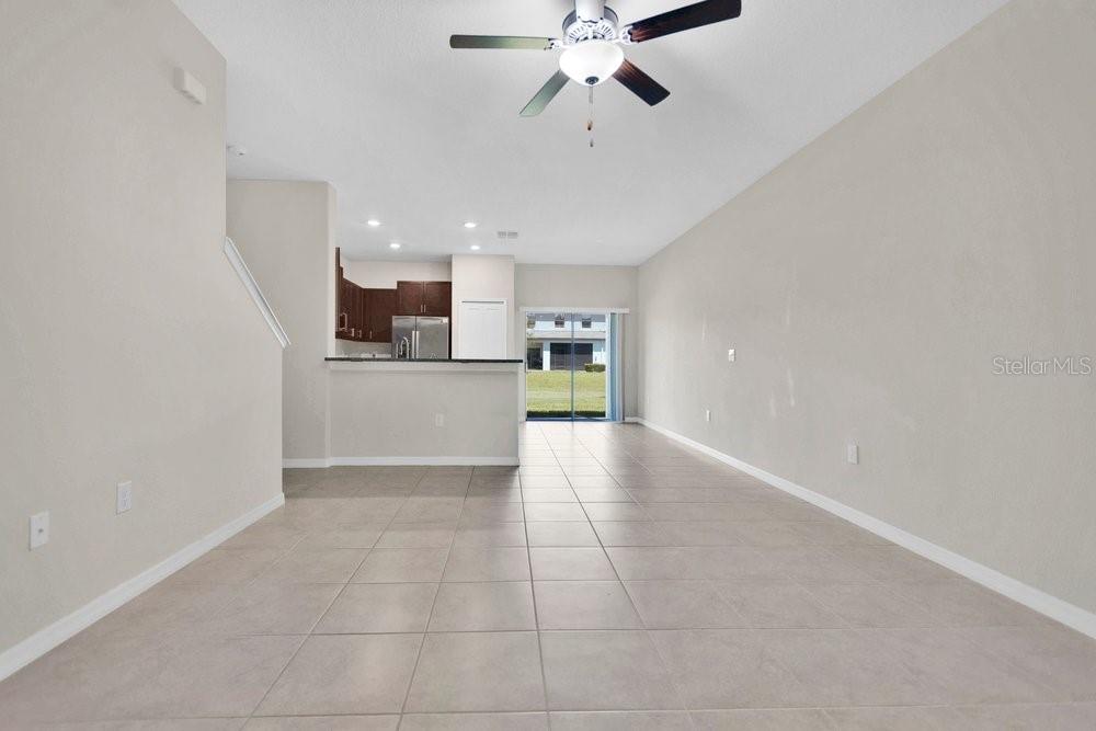 An open-concept living and dining area features light tile flooring, neutral walls, and a kitchen — 9640 MULBERRY MARSH LANE, SUN CITY CENTER, FL