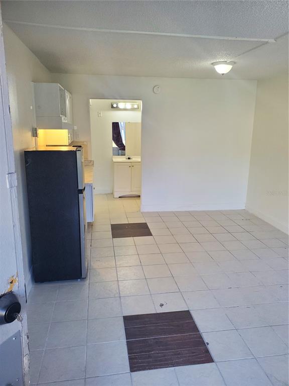A small kitchen features white cabinets, a stainless steel refrigerator, and light-colored tile flooring — 7900 S ORANGE BLOSSOM TRAIL UNIT 1120, ORLANDO, FL