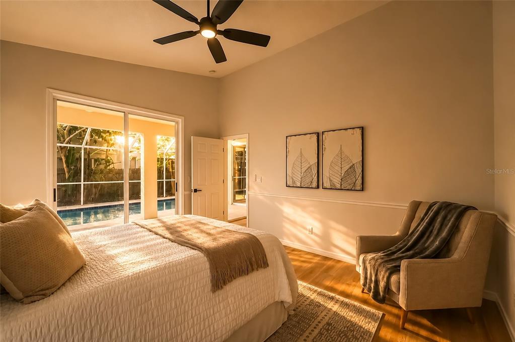 A bedroom features a bed, an armchair, a ceiling fan, and sliding doors to a pool — 1887 WOOD BEND STREET, TARPON SPRINGS, FL