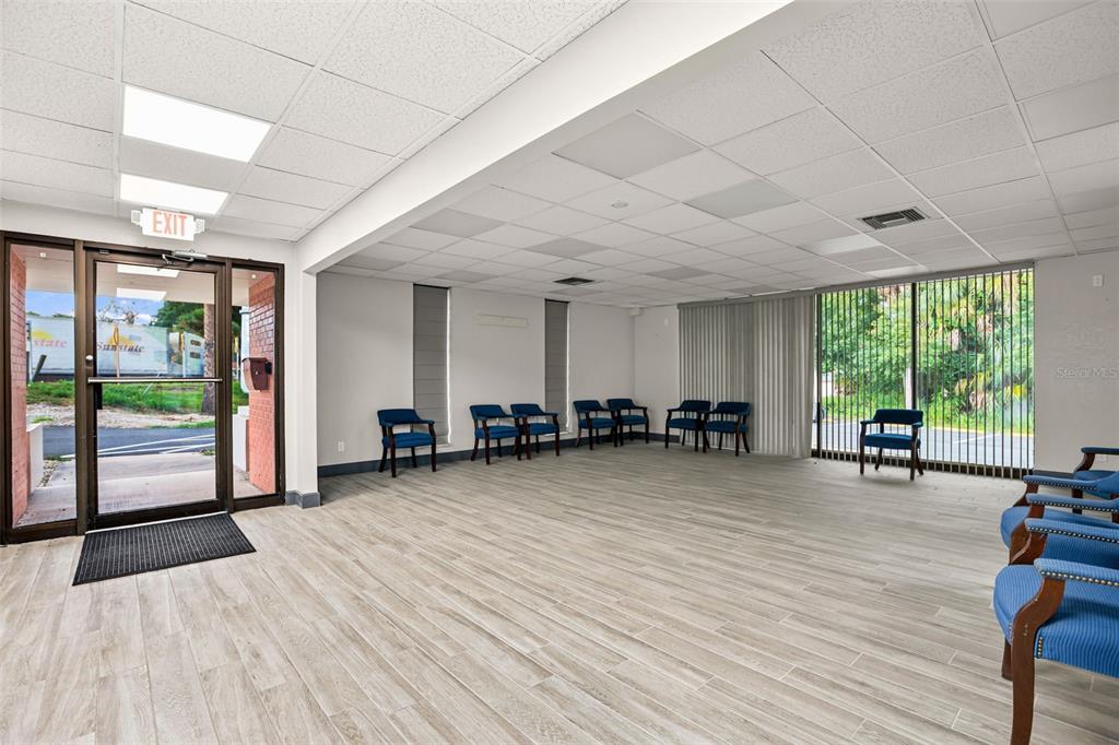 A waiting room with wood-look tile flooring, blue chairs, and a glass entrance door — 901 N GROVE STREET, EUSTIS, FL