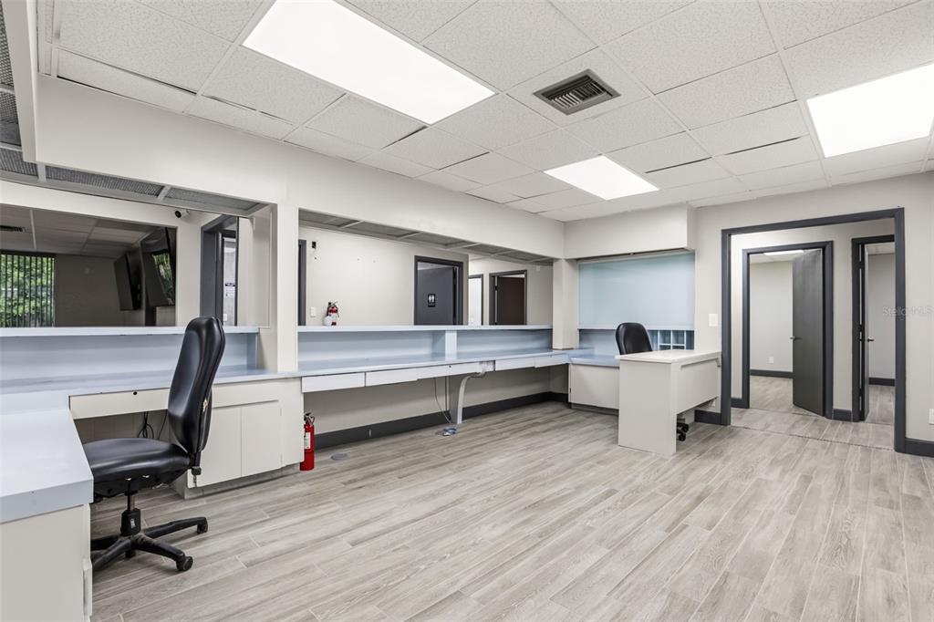 An office space features a long built-in desk, wood-look flooring, and a drop ceiling — 901 N GROVE STREET, EUSTIS, FL