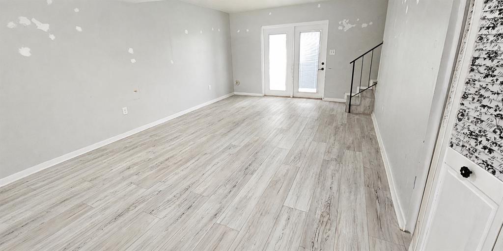 An empty room features light wood-look flooring, gray walls with patch marks, and glass doors — 2405 SE 16TH AVENUE UNIT B, OCALA, FL