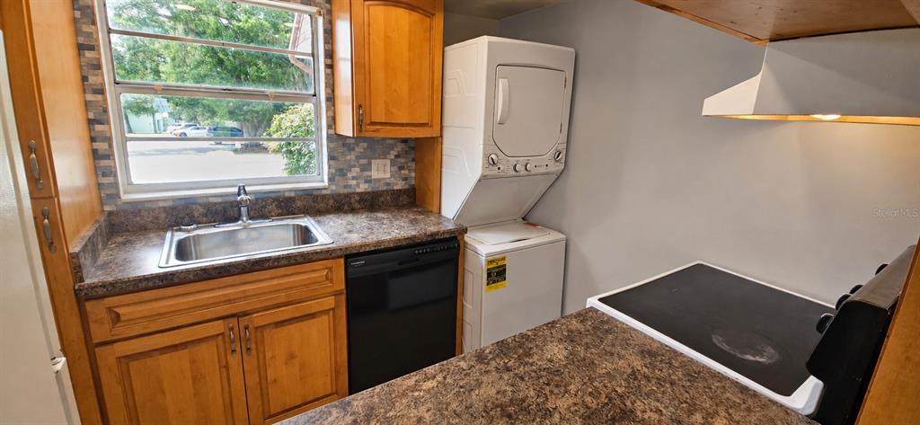 A kitchen features wood cabinets, a sink, a dishwasher, a stacked washer-dryer, and a stove — 2405 SE 16TH AVENUE UNIT B, OCALA, FL