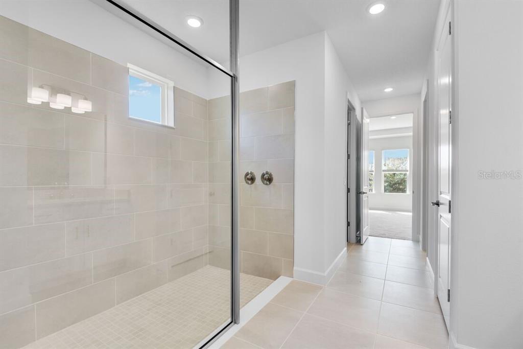 A modern white kitchen features a large island, stainless steel appliances, and light tile flooring — 672 JUNONIA BOULEVARD, NEW SMYRNA BEACH, FL