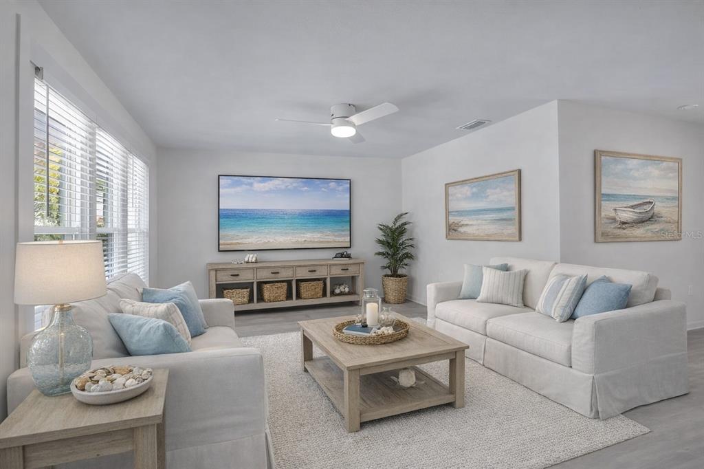 A sunroom features a blue sectional sofa, a round woven coffee table, and waterfront views — 922 CASEY COVE DRIVE, NOKOMIS, FL