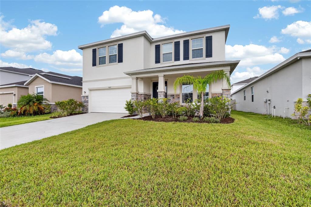 A two-story suburban house with a white exterior, stone accents, and a front-facing garage — 5633 HAWKS CAY STREET, APOLLO BEACH, FL