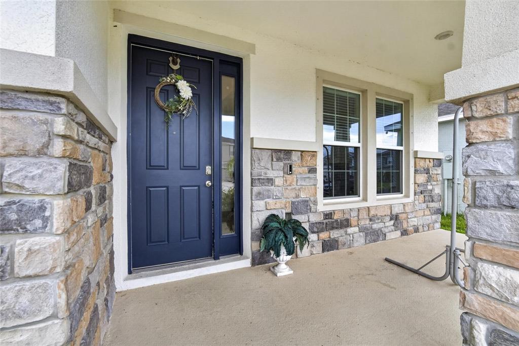 A front porch features a dark blue door, stone veneer siding, and a concrete floor — 5633 HAWKS CAY STREET, APOLLO BEACH, FL