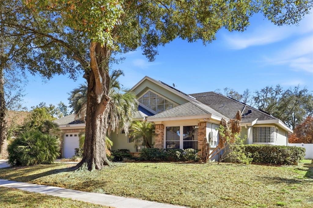 A single-story house with a large tree in the front yard and a triangular window — 8034 LANDGROVE COURT, ORLANDO, FL