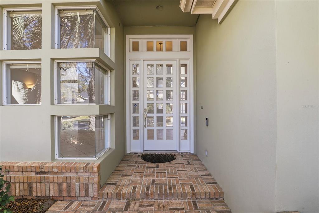A front entrance with a white grid-paneled door, sidelights, and a brick porch — 8034 LANDGROVE COURT, ORLANDO, FL