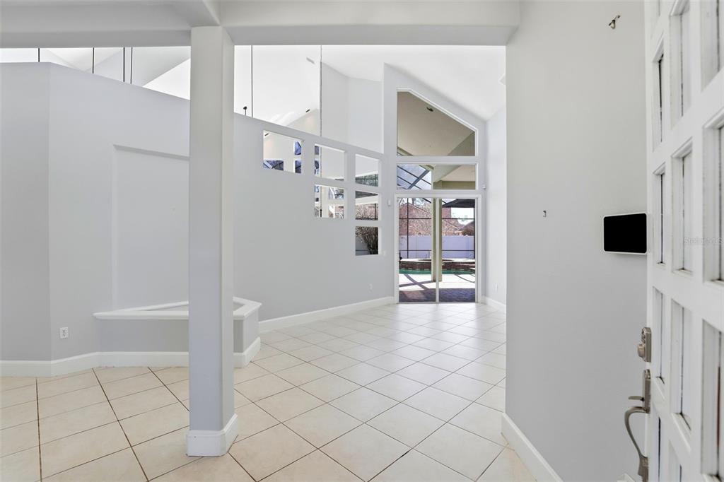 An entryway with light tile flooring leads to a living area with high vaulted ceilings — 8034 LANDGROVE COURT, ORLANDO, FL