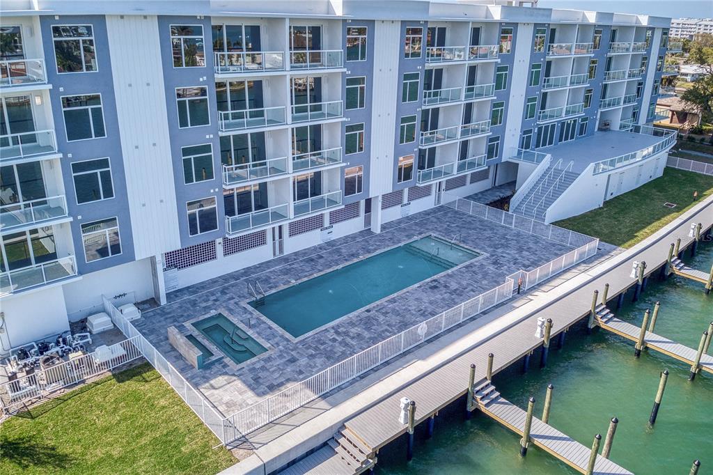 An aerial view of a multi-story apartment building with a swimming pool and boat docks — 415 ISLAND WAY UNIT 206, CLEARWATER BEACH, FL