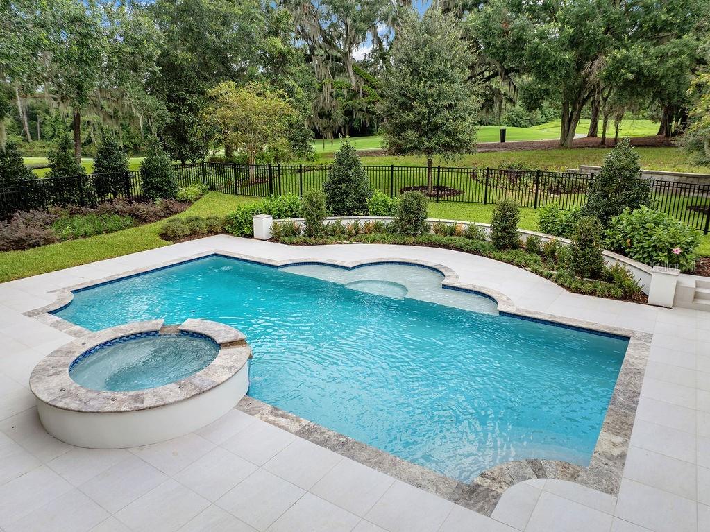 A swimming pool with an attached spa sits on a patio overlooking a fenced backyard — 4015 NW 85TH TERRACE, OCALA, FL