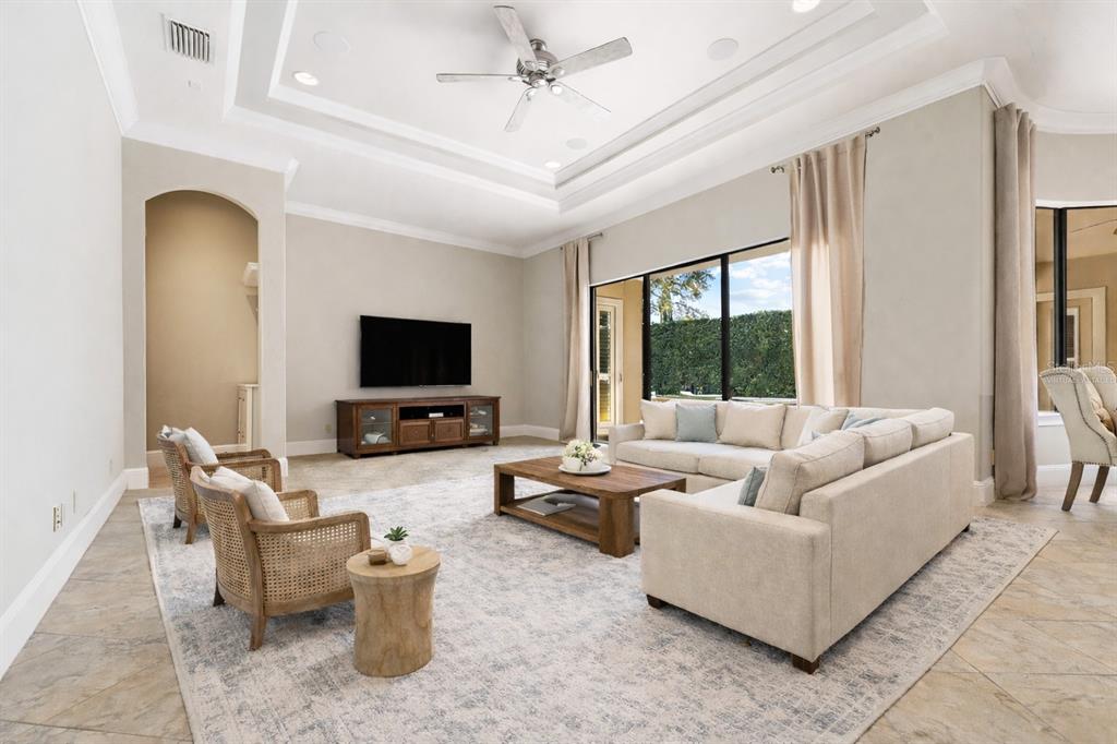 A spacious living room features a tray ceiling, tile flooring, and a large sectional sofa — 6560 LAKE BURDEN VIEW DRIVE, WINDERMERE, FL